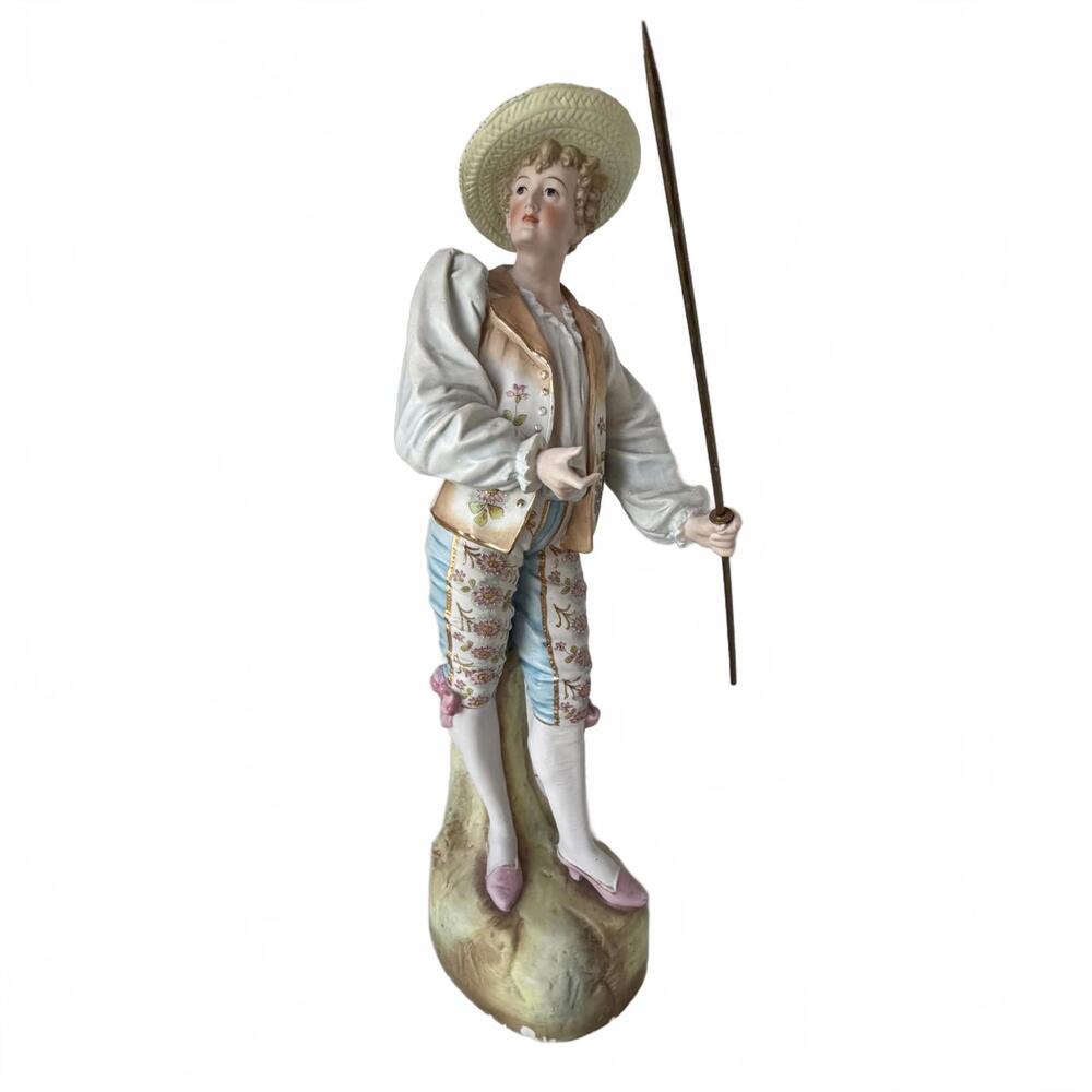 Bisque porcelain figurine of a pastoral boy with a straw hat and stick.